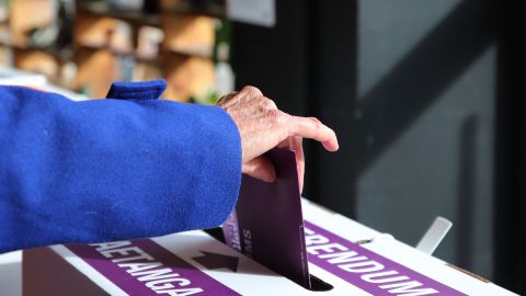 A woman places her referendum voting paper in the ballot box as advance voting begins on October 3 in Wellington, New Zealand.