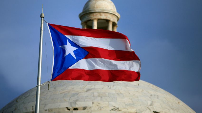 FILE - In this July 29, 2015 file photo, the Puerto Rican flag flies in front of Puerto Rico's Capitol as in San Juan, Puerto Rico. A federal control board that oversees Puerto Rico's finances approved on Wednesday, July 1, 2020, a new budget that largely suspends austerity measures and government cuts for one year as the U.S. territory struggles to recover from hurricanes, earthquakes and the pandemic. (AP Photo/Ricardo Arduengo, File)