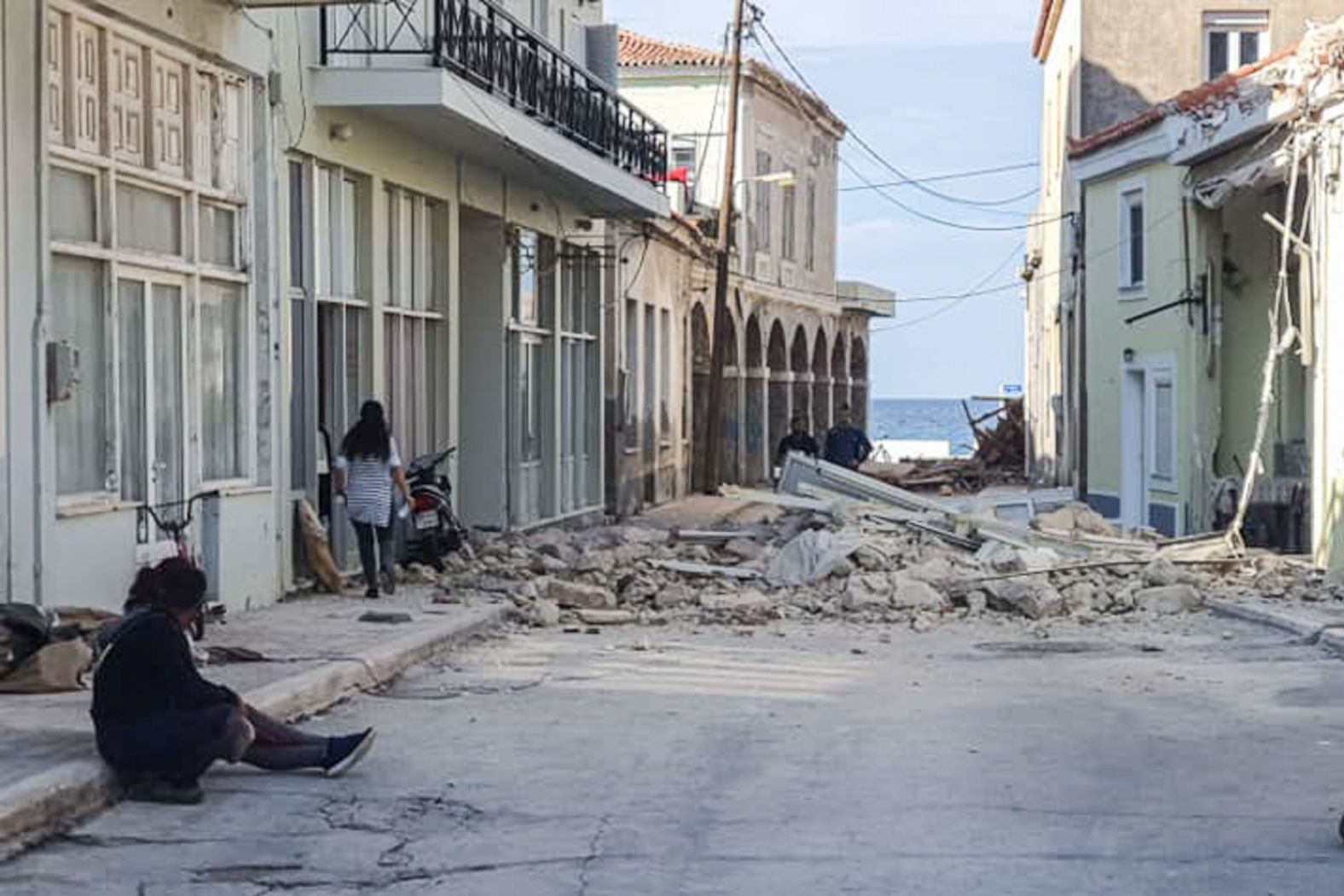 People walk past a damaged house after the earthquake struck near Samos.