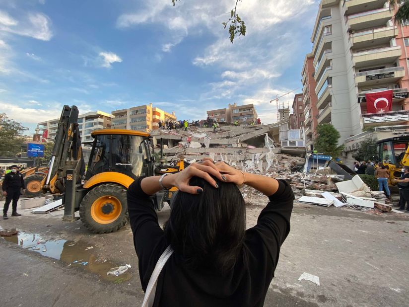 A woman reacts as search-and-rescue teams work at a building site in Izmir.