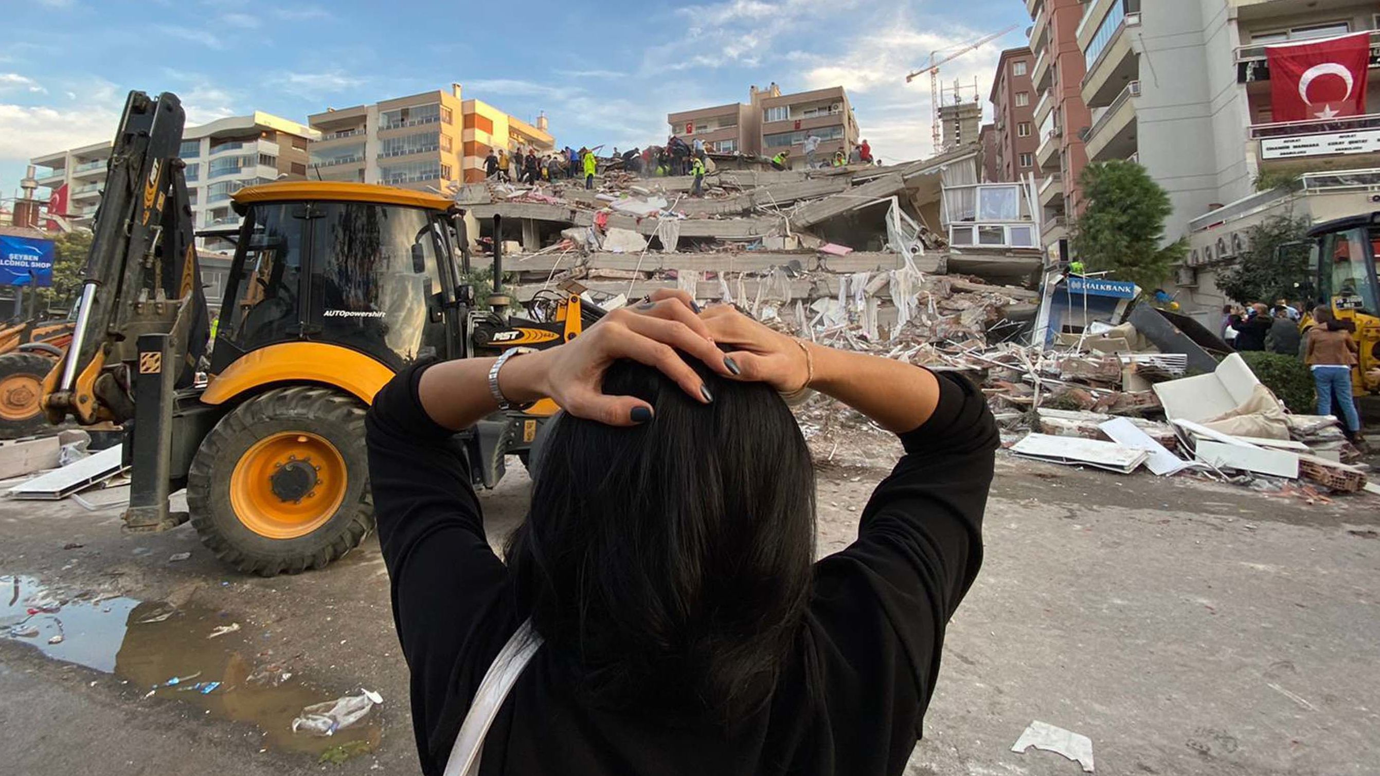 A woman reacts as search-and-rescue teams work at a building site in Izmir.