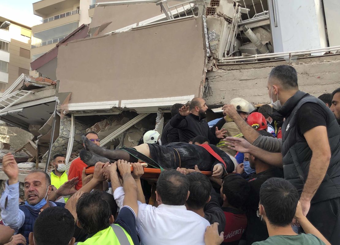 Rescue workers and local people carry a wounded person found in the debris of a collapsed building, in Izmir, on Friday.
