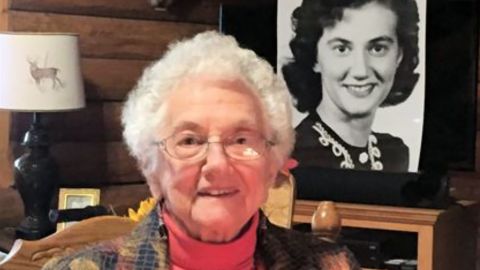 Florence Sobralske sits in front of a photo of herself as a younger woman.