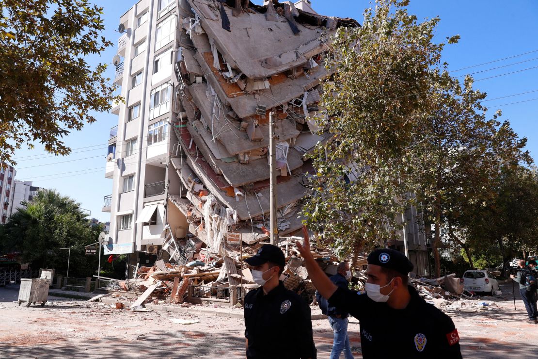 Members of security forces walk past a collapsed building in Izmir, Turkey, on Saturday.