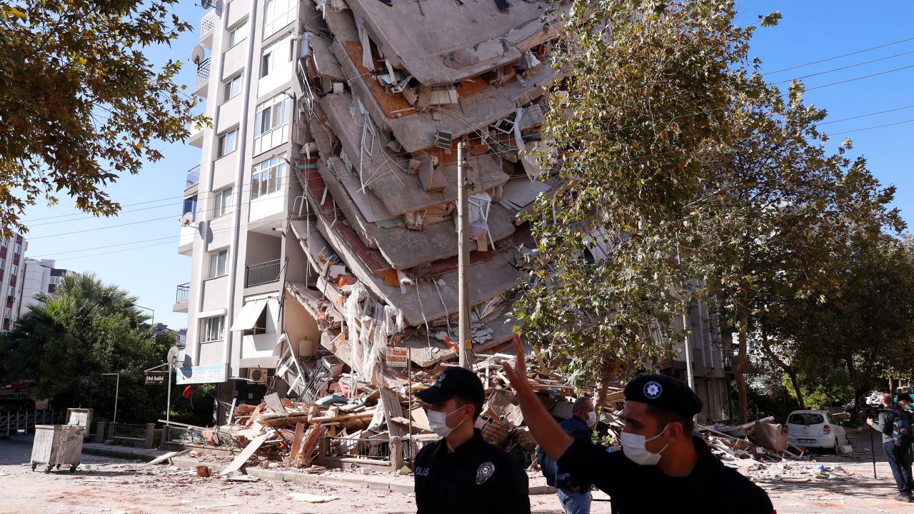 Members of security forces walk past a collapsed building in Izmir, Turkey, on Saturday.