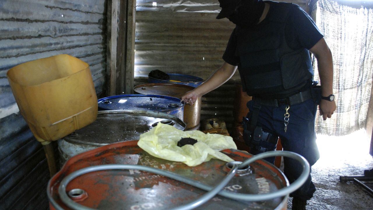 Imagen ilustrativa. Un policía inspecciona barriles que contienen combustible diésel robado, almacenados en un taller de reparación de neumáticos, durante una operación en el municipio de Apodaca, vecino de Monterrey, el 4 de julio de 2011.