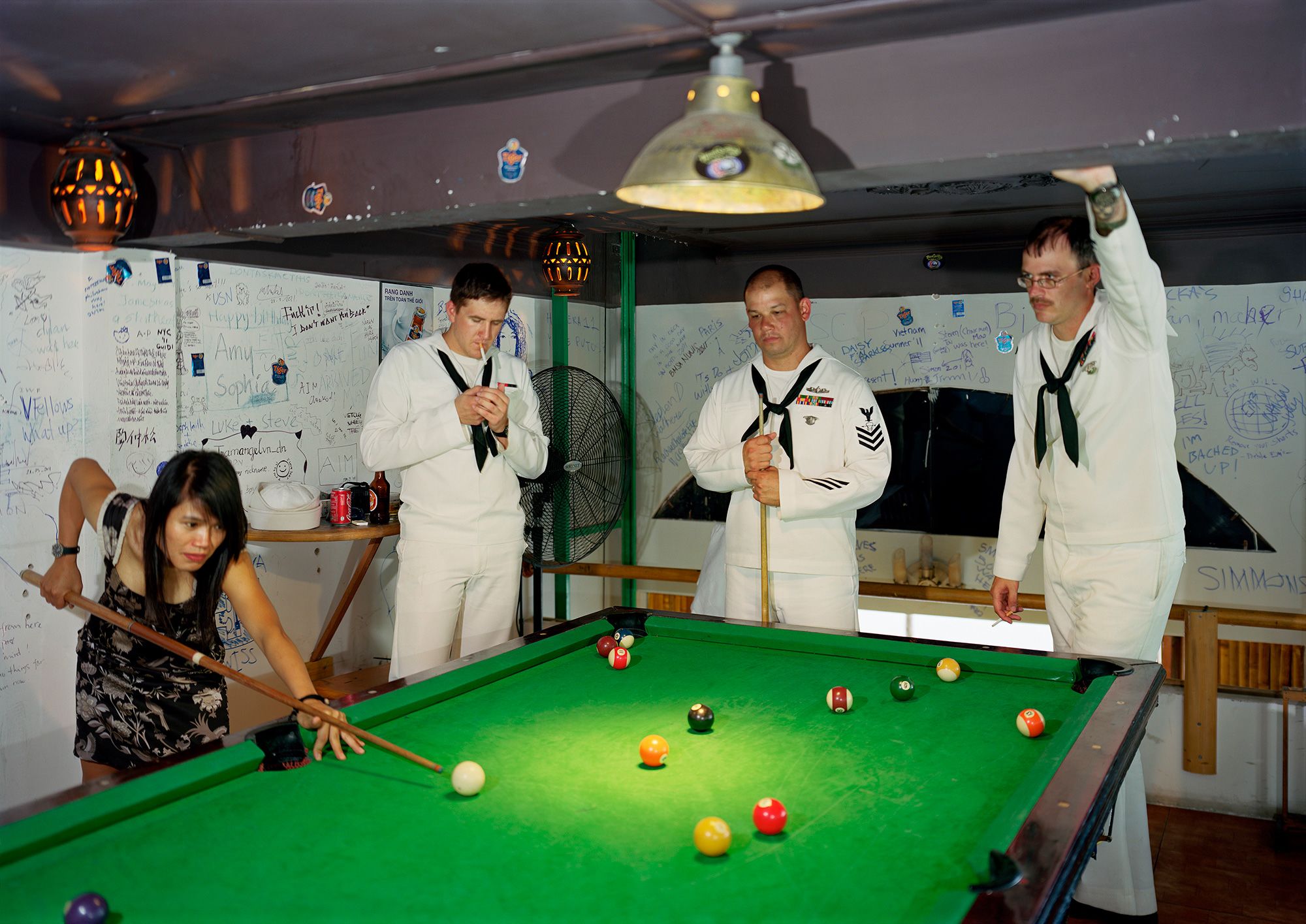 Sailors from the USS Preble play pool with a woman in a bar in Da Nang, Vietnam; a photo from Lê's "Events Ashore" series.