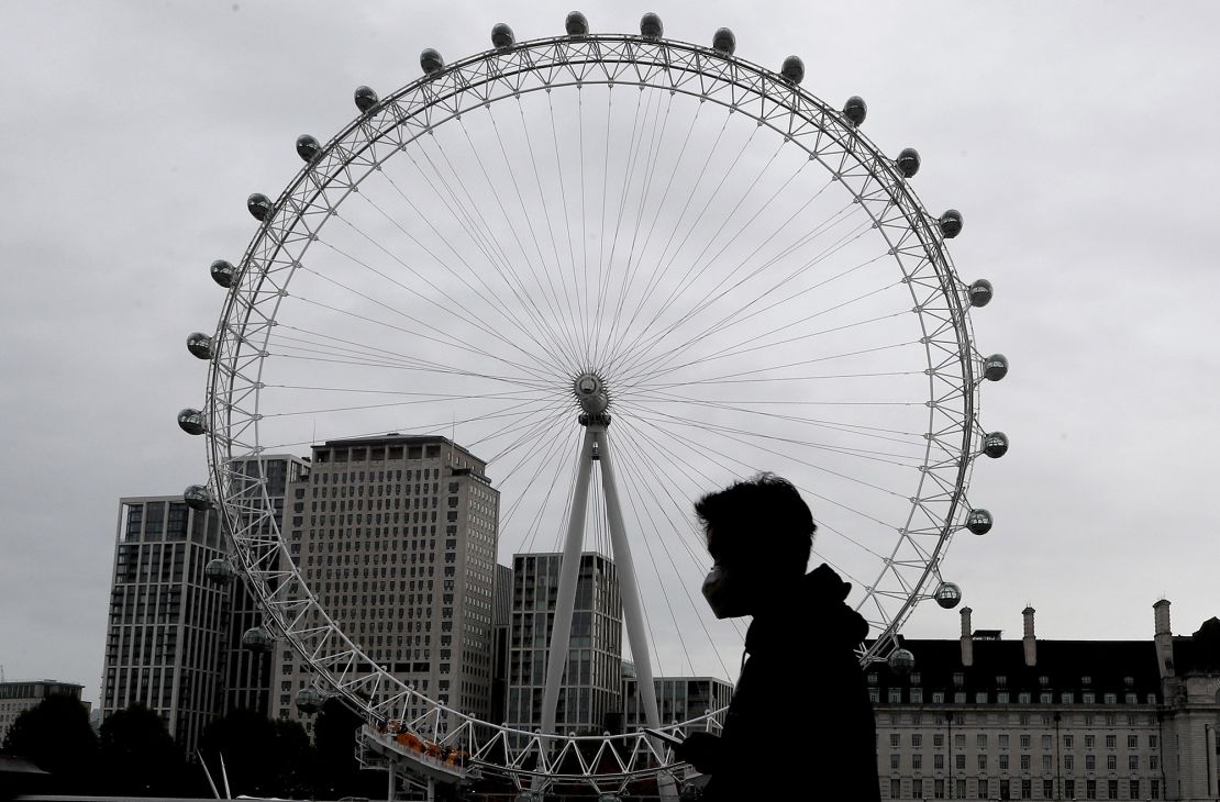 A man wearing a mask passes the London Eye on Thursday as England prepares for a month-long lockdown.