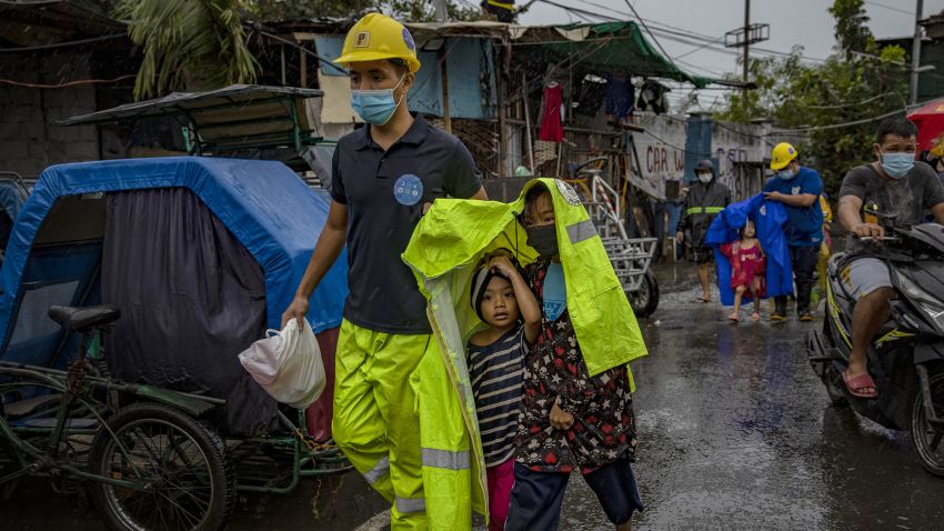 MANILA, PHILIPPINES - NOVEMBER 01: A rescue worker covers children in a raincoat as they evacuate before Typhoon Goni hits on November 1, 2020 in Manila, Philippines. Super Typhoon Goni, this year's most powerful storm in the world,  has made landfall in the Philippines with wind gusts of up to 165 miles per hour early Sunday. At least two people have been killed so far and hundreds of thousands have been evacuated ahead of the storm. (Photo by Ezra Acayan/Getty Images)