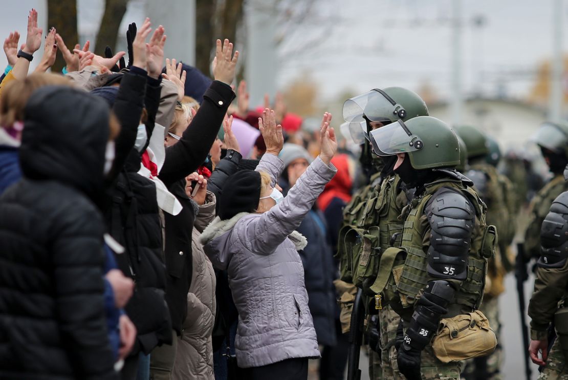 Demonstrators stand with their hands up in front of riot police in Minsk on Sunday.
