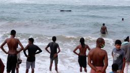Sri Lankans watch as some attempt to push a beached whale back to deep waters in the Indian Ocean in Panadura, on outskirts of Colombo, Sri Lanka, Tuesday, Nov. 3, 2020. Sri Lanka is postponing the opening of schools amid a surge of COVID-19 patients from two clusters in the capital Colombo and suburbs. (AP Photo/Eranga Jayawardena)