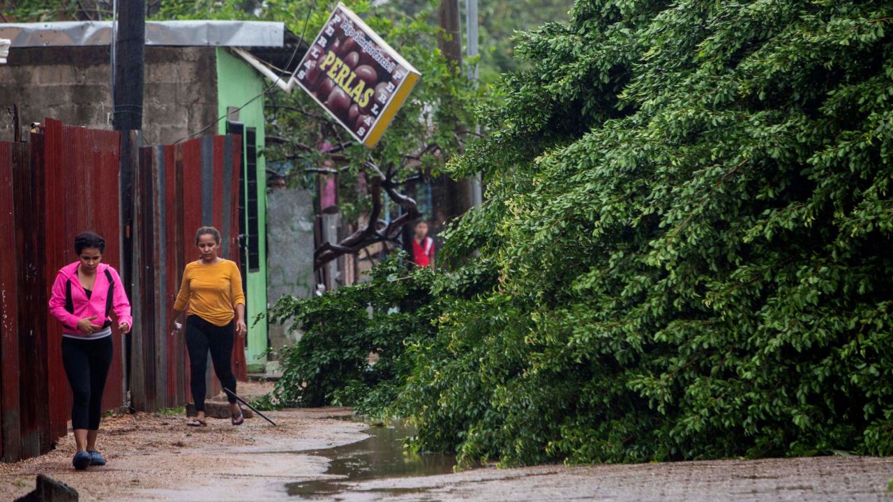 Women walk next to fallen trees Tuesday morning in Puerto Cabezas, Nicaragua, after winds from Hurricane Eta raked the area.