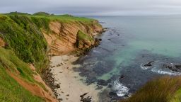 Elevated, panoramic view of a bay with red, sandstone cliffs in the Chatham islands, New Zealand.