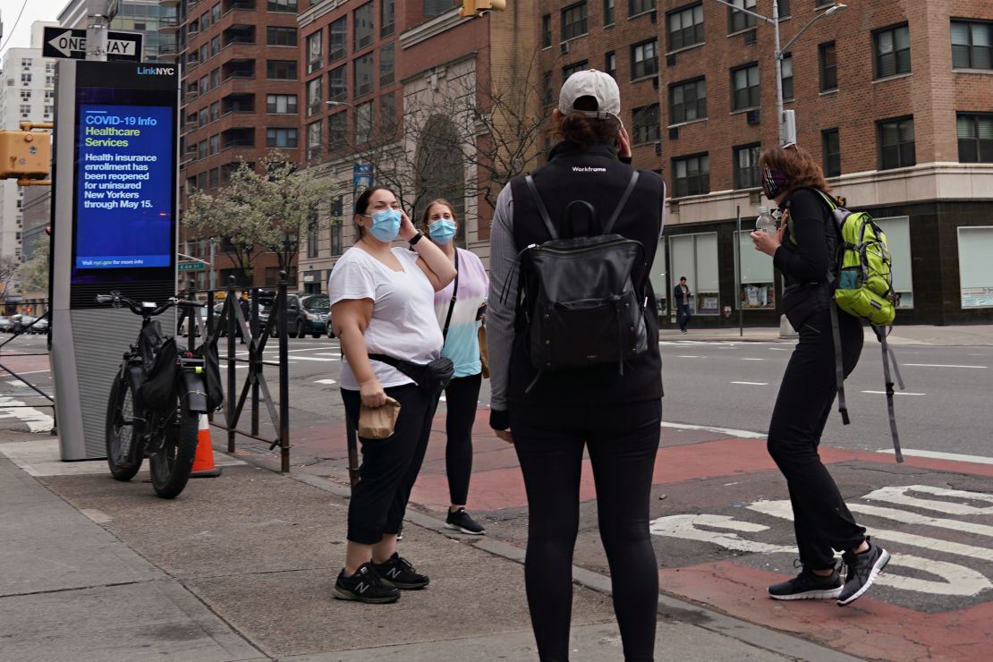 Women wearing protective masks speak on the street in New York City on April 5.