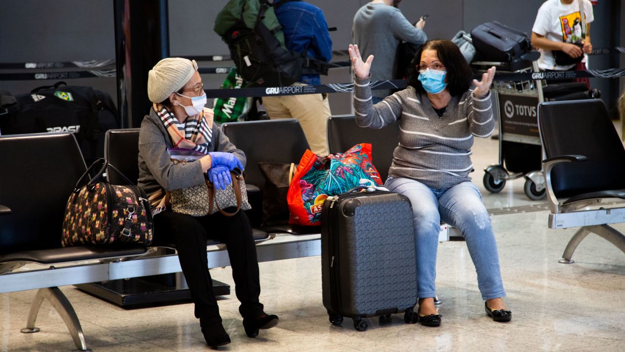 Passengers wear protective face masks while talking in Brazil's São Paulo/Guarulhos International Airport on March 15.