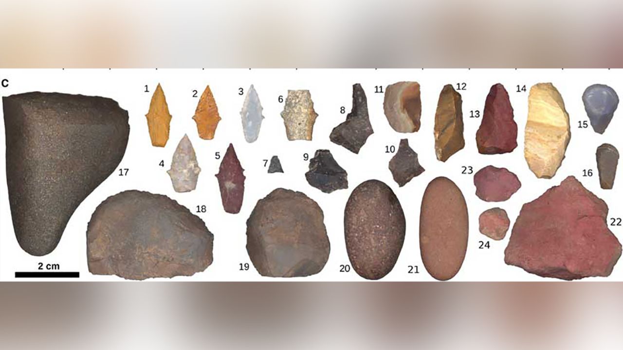 This illustration shows tools recovered from the burial pit floor including projectile points (1 to 7), a possible backed knife (14), thumbnail scrapers (15 and 16), scrapers/choppers (17 to 19), burnishing stones (17, 20, and 21) and red ocher nodules (22 to 24).