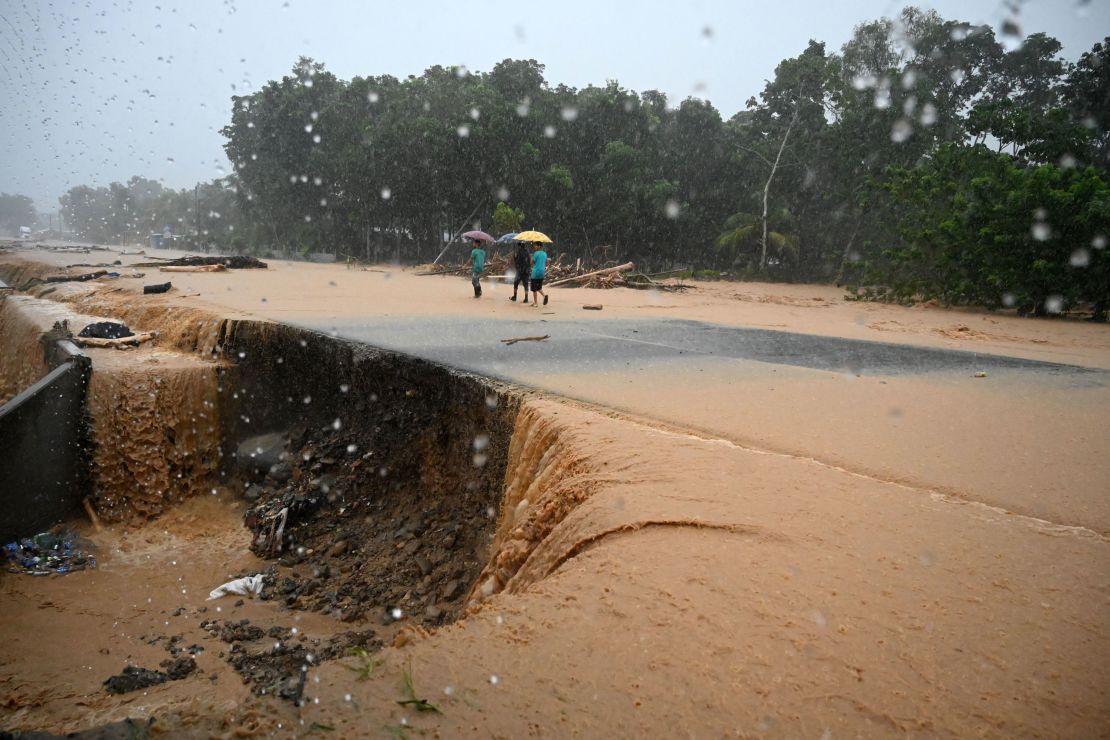 Men walk along a flooded road Wednesday after a river overflowed courtesy of rains from Hurricane Eta in Toyos, Honduras.  