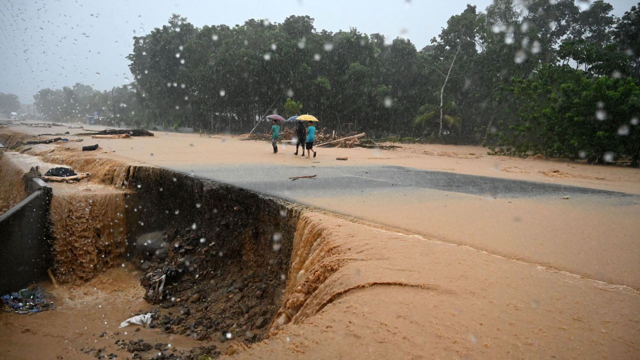 Men walk along a flooded road Wednesday after a river overflowed courtesy of rains from Hurricane Eta in Toyos, Honduras.