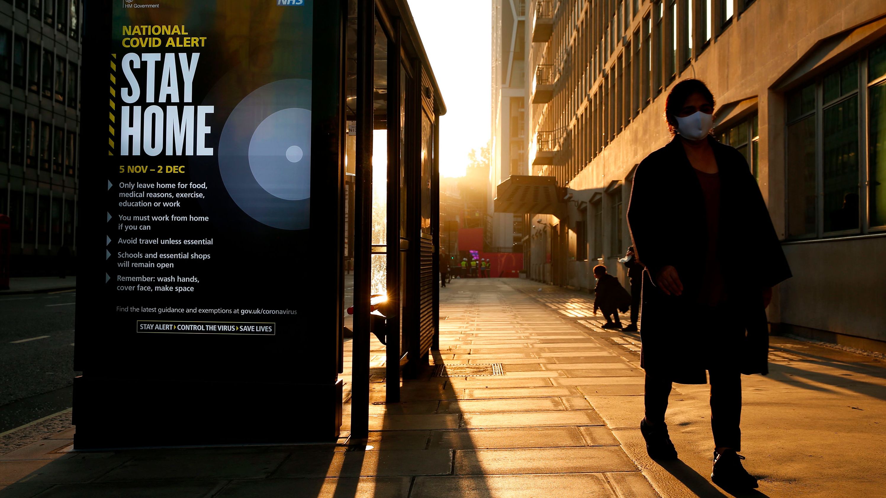 A pedestrian wearing a mask passes a digital display in London showing the new measures as England enters a second coronavirus lockdown on November 5.