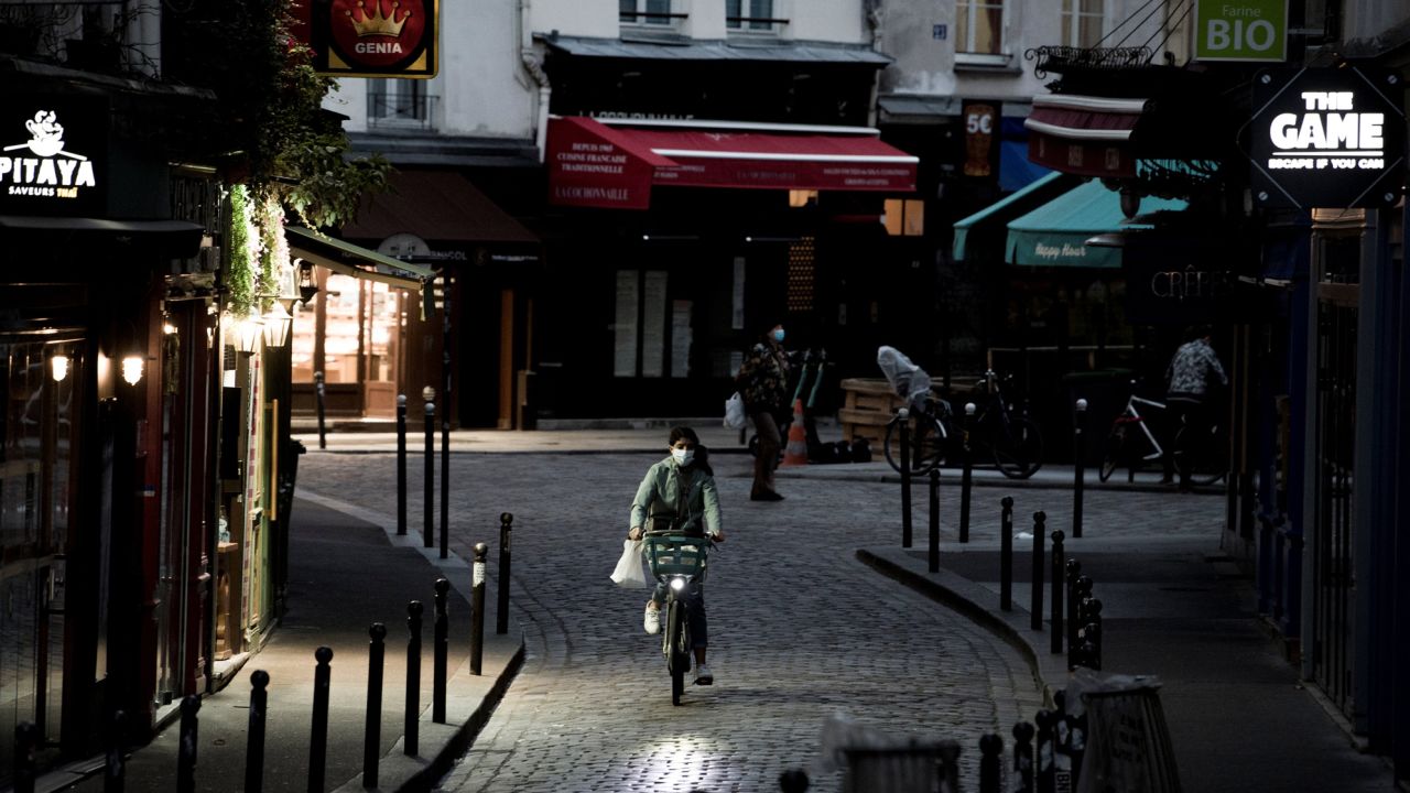 A woman rides a bike along an empty street in the district of St. Michel in Paris on November 3, the fifth day of France's lockdown.