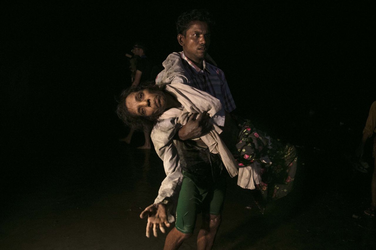 Sona Banu is carried ashore on September 27 by Nobi Hossain after crossing the Naf River by boat from Myanmar to near Cox's Bazar, Bangladesh.