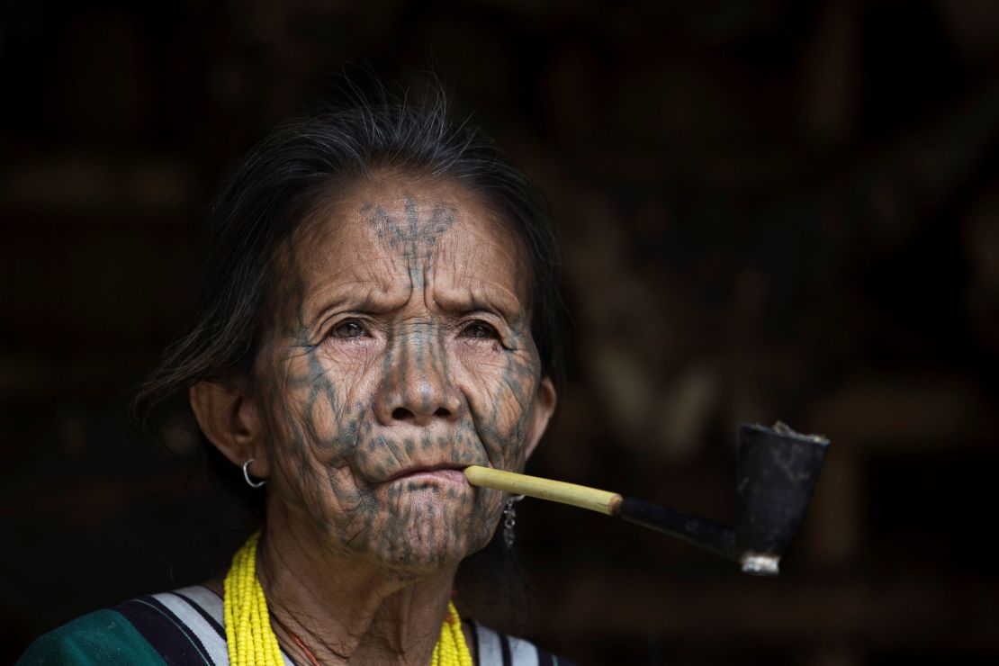 This photo taken on March 3, 2020 shows a tattooed Chin ethnic woman smoking at her house in a village of Chin State, western Myanmar. 