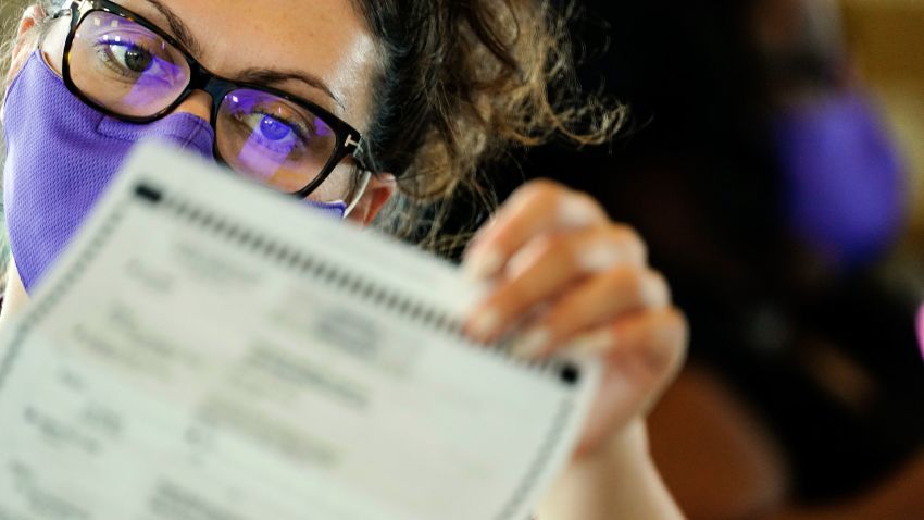 An election worker examines ballots as vote counting in the general election continues at State Farm Arena on Thursday, Nov. 5, 2020, in Atlanta. (AP Photo/Brynn Anderson)