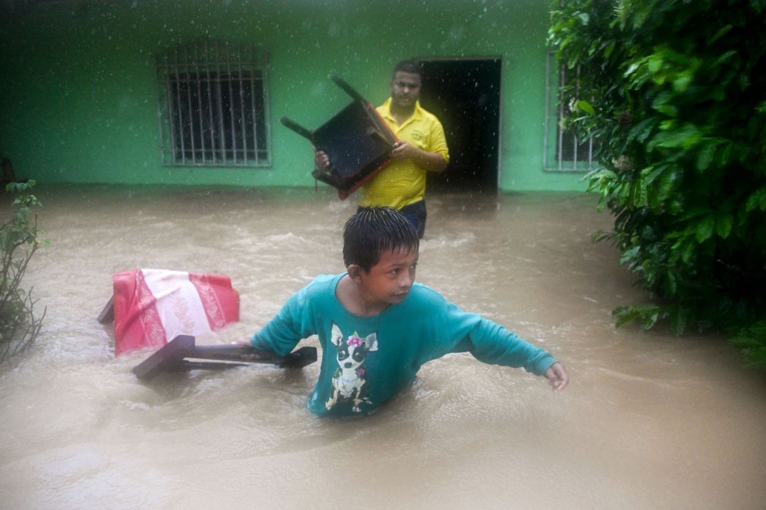A family saves their belongings from a flooded house after heavy rains caused by Eta in Guatemala.