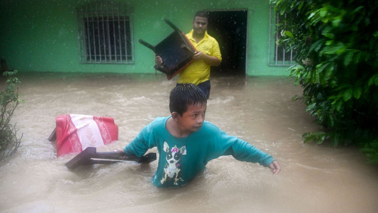 A family saves their belongings from a flooded house after heavy rains caused by Eta in Guatemala.