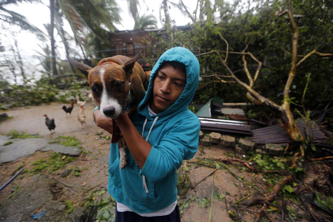 A man carries a dog to safety after Eta slams Nicaragua.
