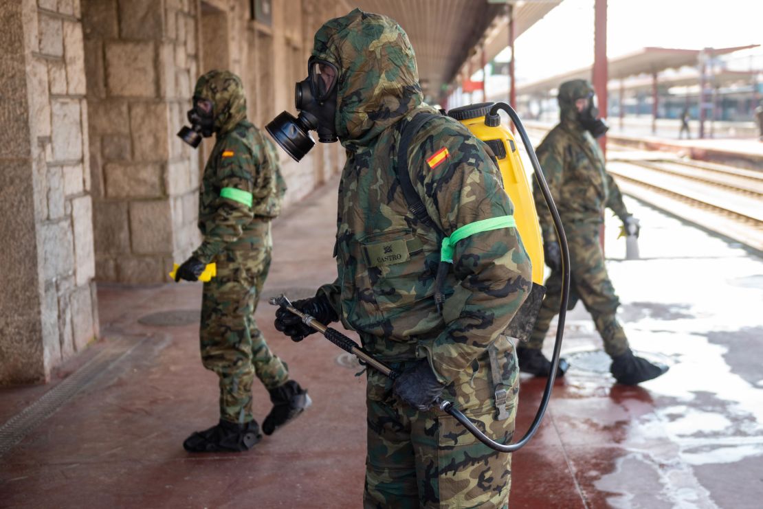 Military officers wearing protective suits and masks disinfect Irun train station in northern Spain on March 28, 2020.