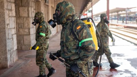 Military officers wearing protective suits and masks disinfect Irun train station in northern Spain on March 28, 2020.