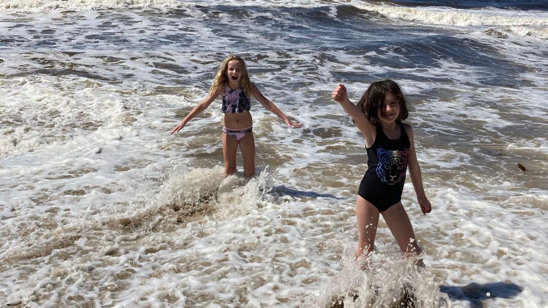 Haylee, left, plays with sister Maddie in the surf. 