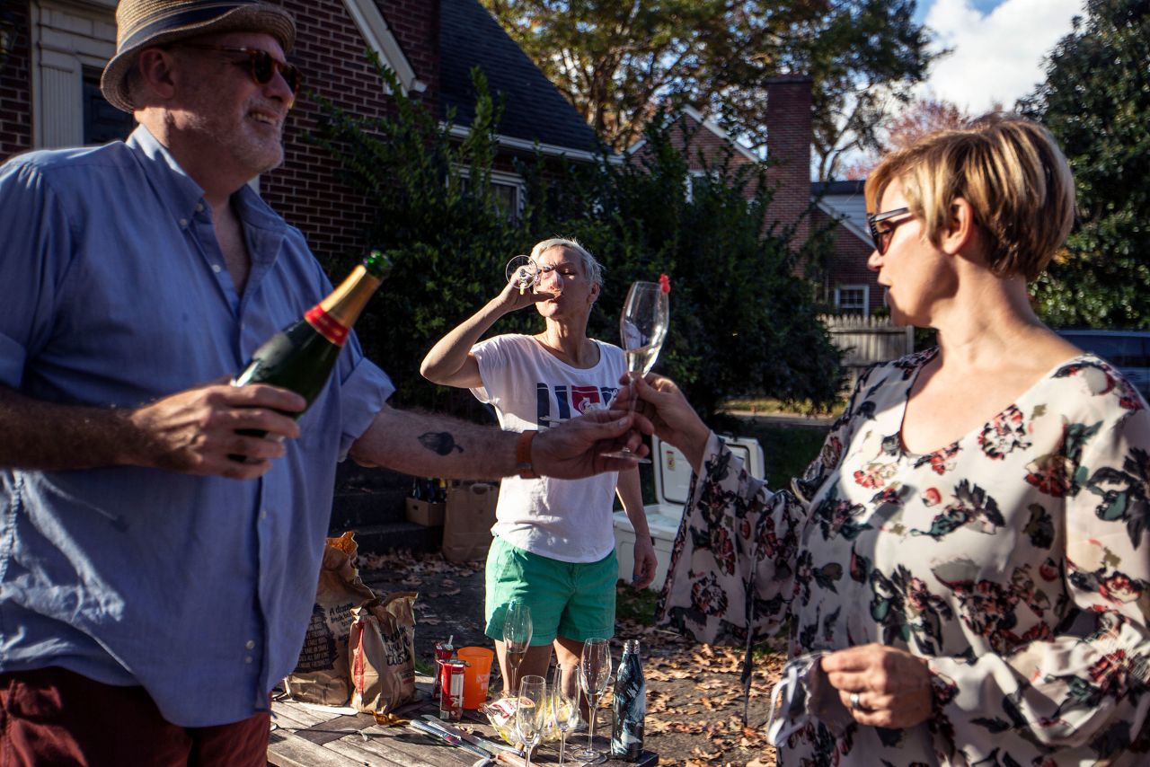 From left, Damon Akins, Colleen Trimble and Kathryn Shields drink champagne as they celebrate Biden's win in Greensboro, North Carolina.