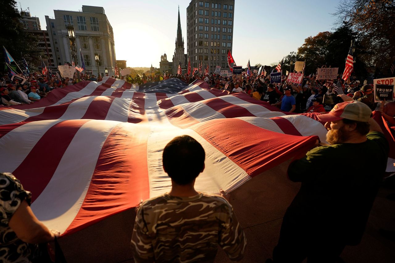 Supporters of President Donald Trump unfurl a giant American flag outside the State Capitol in Harrisburg, Pennsylvania, after Biden's win was projected on November 7.