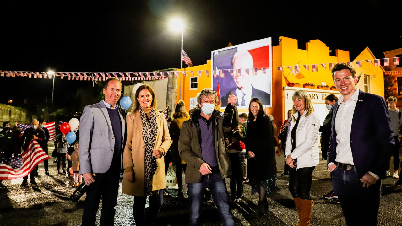 Joe Blewitt, (left), a cousin of Joe Biden, celebrates with (from left) his wife Deirdre, Smiler Mitchell, Laurita Blewitt, Emer Bourke, and local politician Mark Duffy. Behind them is a mural of Biden, recently created by Mitchell and another local artist, Leslie Lackey. 