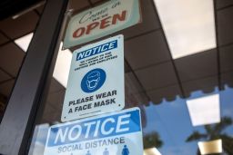 Signs reminding the public to practice social distancing and wear a mask on a storefront in Miami, Wednesday, November 4. 