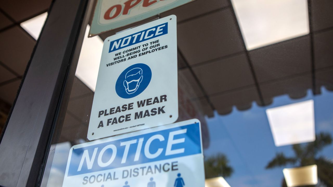 Signs reminding the public to practice social distancing and wear a mask on a storefront in Miami, Wednesday, November 4. 
