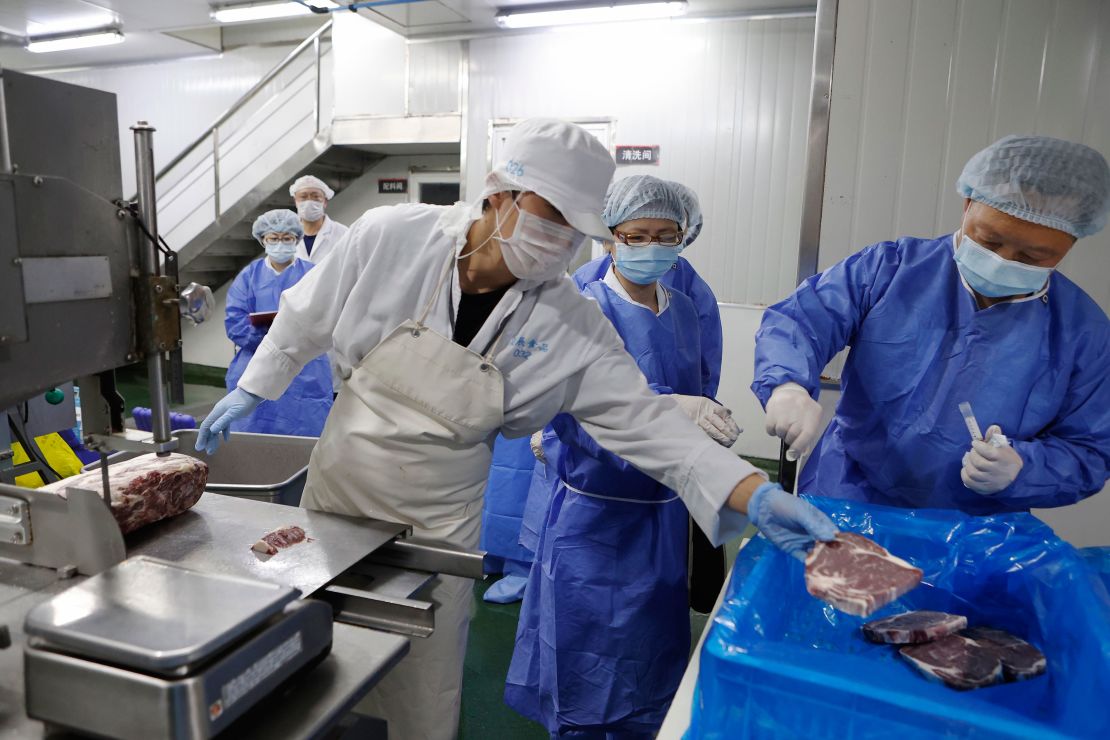 Medical workers wearing protective suits collect samples from imported frozen beef for coronavirus tests at a food factory in Shanghai, China.