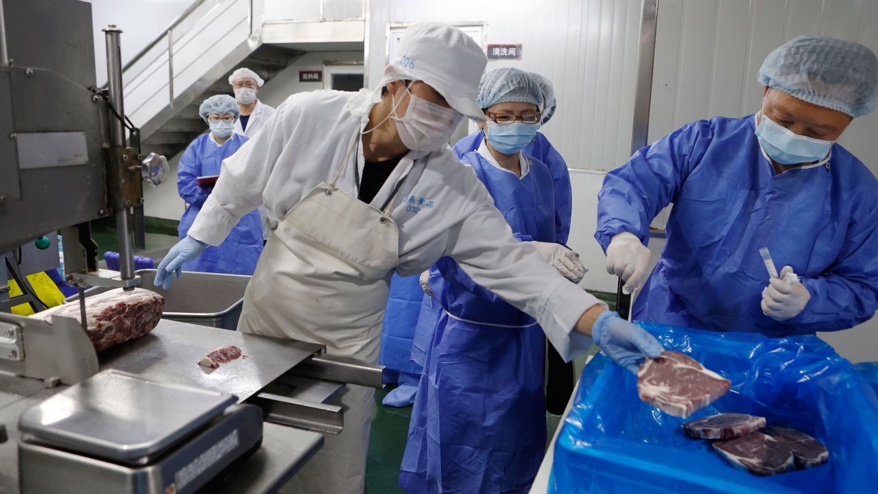 Medical workers wearing protective suits collect samples from imported frozen beef for coronavirus tests at a food factory in Shanghai, China.