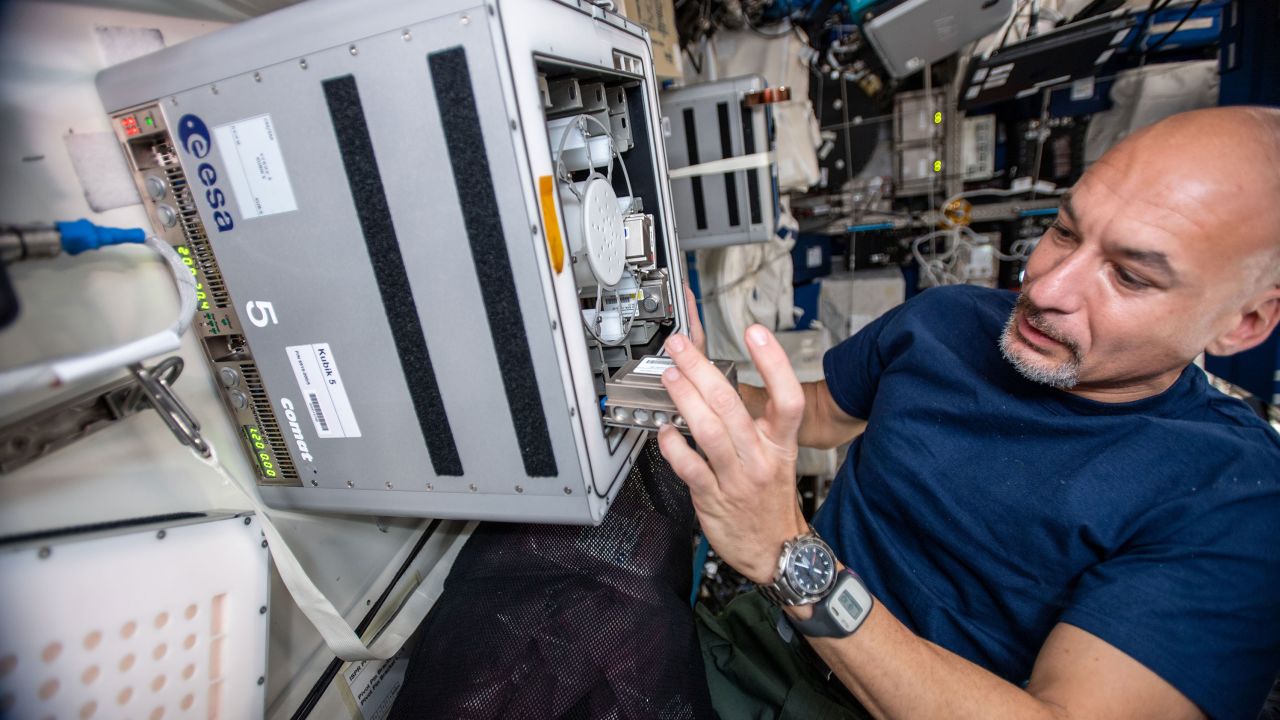European Space Agency astronaut Luca Parmitano on the International Space Station is shown here conducting the experiment with the biomining reactors.
