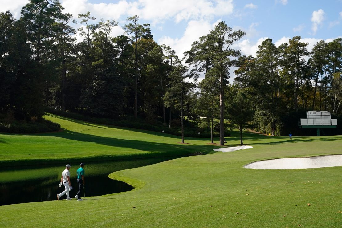 DeChambeau and Tiger Woods walk up the 15th fairway during a practice round at the Masters.