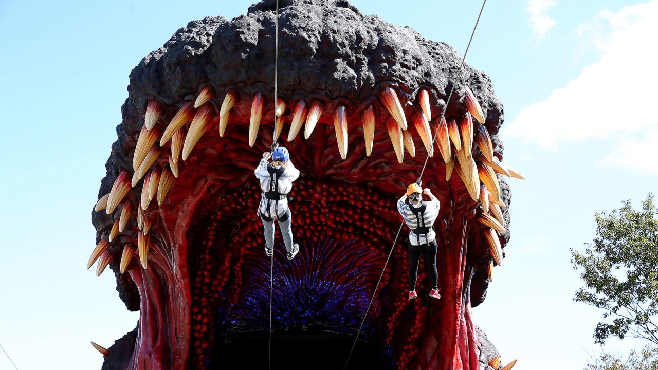 AWAJI, JAPAN - OCTOBER 11: Visitors ride through the mouth of Godzilla replica as a part of 'National Awaji Island Institute of Godzilla Disaster' zip-line at the Nijigen no Mori theme park on Awaji Island on October 11, 2020 in Awajishima, Hyogo Prefecture, Japan. 'National Awaji Island Institute of Godzilla Disaster' featuring 'life-size' Godzilla replica zipline is the latest addition to this park featuring attractions themed around Japanese anime works. (Photo by Buddhika Weerasinghe/Getty Images)