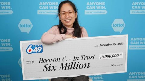 Heewon (Theresa) Choi holds up a check for $6 million after she and three of her coworkers won big on October 31, 2020. 
