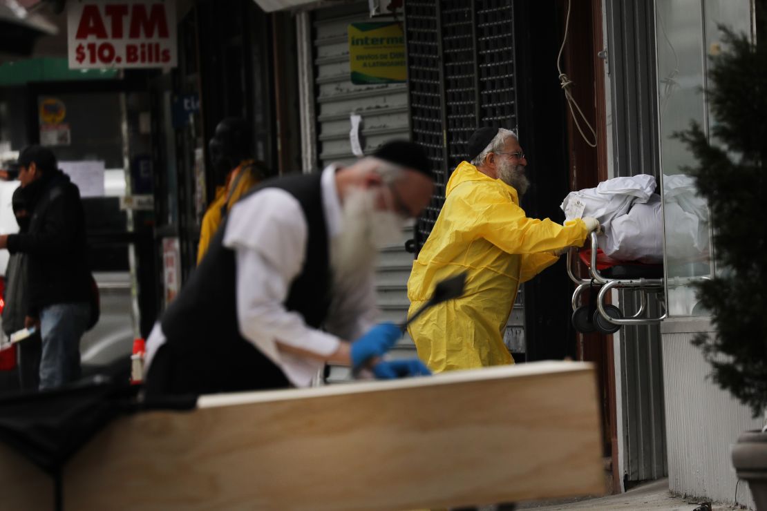 Orthodox Jewish men move a wooden casket from a hearse at a funeral home on April 5, 2020 in the Brooklyn borough of New York City.