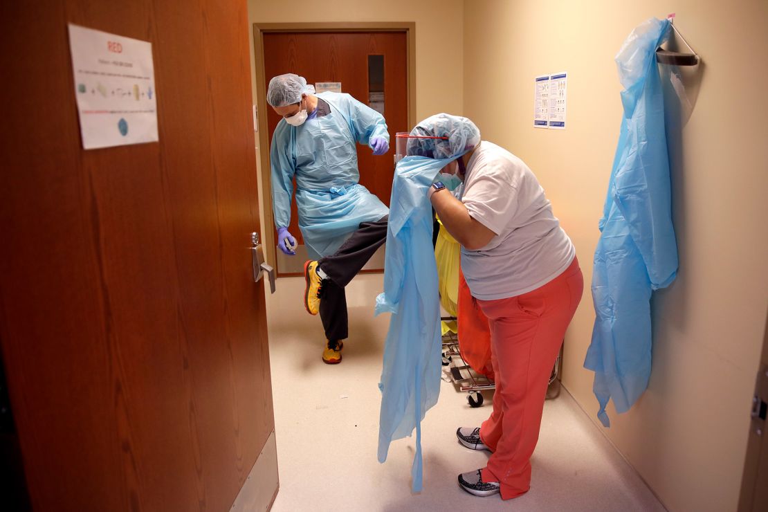 Dr. Drew Miller sprays disinfectant on his shoes while respiratory therapist Jade Carabajal-Richter removes protective gear at Kearny County Hospital in Lakin, Kansas.