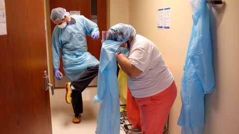 Dr. Drew Miller sprays disinfectant on his shoes while respiratory therapist Jade Carabajal-Richter removes protective gear at Kearny County Hospital in Lakin, Kansas.