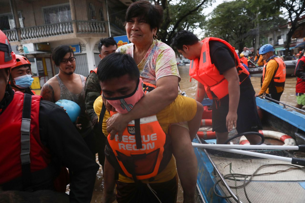 A rescuer carries a woman out of a boat in Marikina.