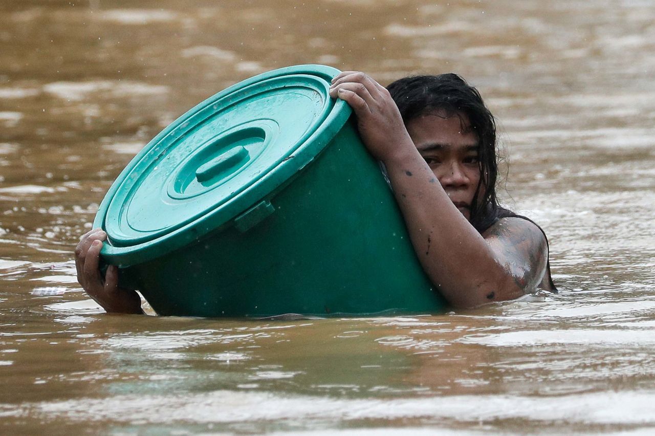 A person uses a plastic container to stay afloat in Marikina.