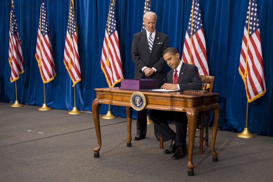 Then Vice President Joe Biden stands with President Barack Obama as he signs $787 billion stimulus package in February 2009.